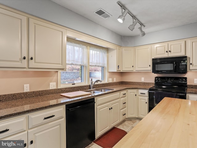 kitchen with dark stone counters, sink, cream cabinets, and black appliances