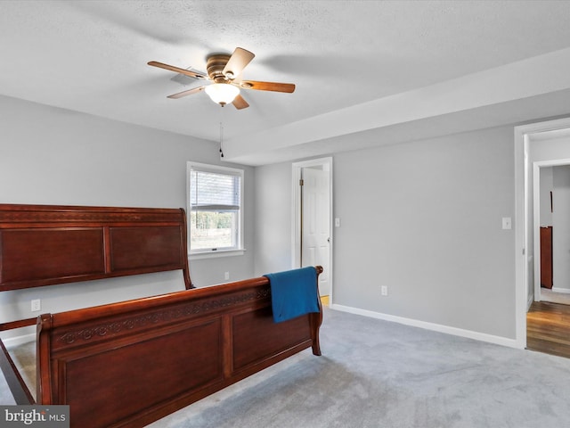 bedroom featuring ceiling fan, light colored carpet, and a textured ceiling