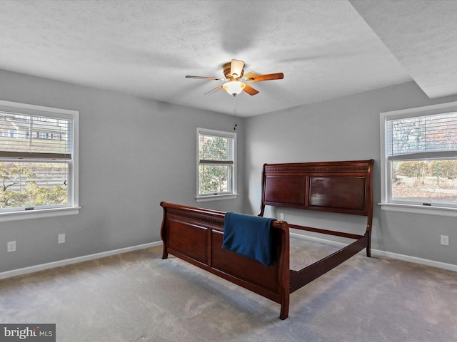 carpeted bedroom featuring multiple windows, ceiling fan, and a textured ceiling