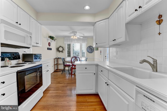 kitchen with sink, white cabinets, light hardwood / wood-style floors, kitchen peninsula, and white appliances