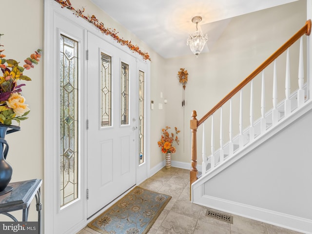 tiled entrance foyer with an inviting chandelier