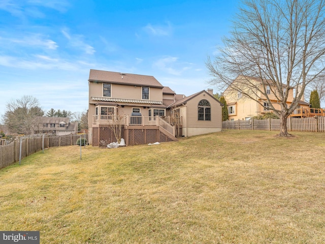 rear view of property featuring a wooden deck and a lawn