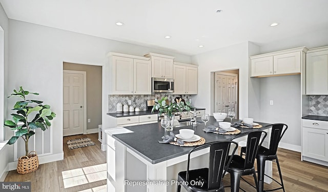 kitchen featuring backsplash, white cabinetry, a center island, and light wood-type flooring