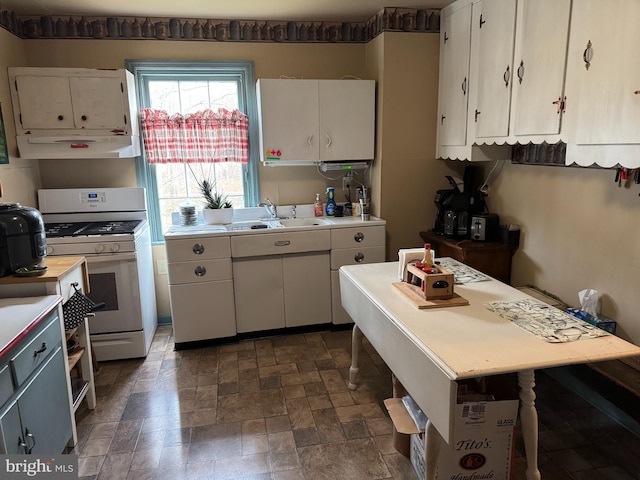 kitchen featuring white cabinetry, sink, and white gas stove