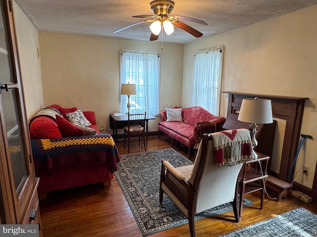 living area featuring dark hardwood / wood-style flooring, ceiling fan, and a textured ceiling