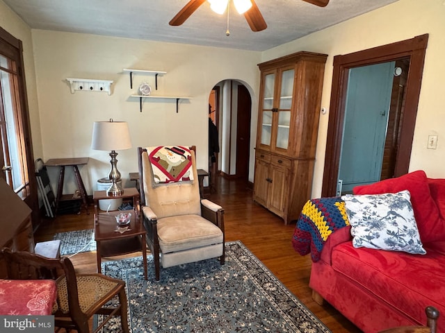 living room featuring dark wood-type flooring and ceiling fan