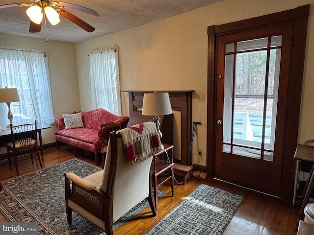 living room featuring hardwood / wood-style flooring, a textured ceiling, and ceiling fan