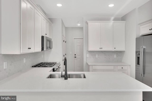 kitchen featuring white cabinetry, appliances with stainless steel finishes, sink, and kitchen peninsula