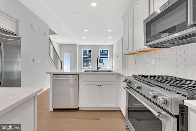 kitchen featuring appliances with stainless steel finishes, sink, white cabinets, and light stone counters