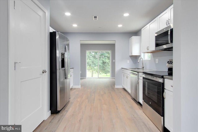 kitchen featuring white cabinetry, sink, light hardwood / wood-style floors, and appliances with stainless steel finishes