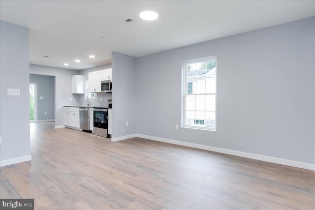 unfurnished living room featuring sink and light hardwood / wood-style floors