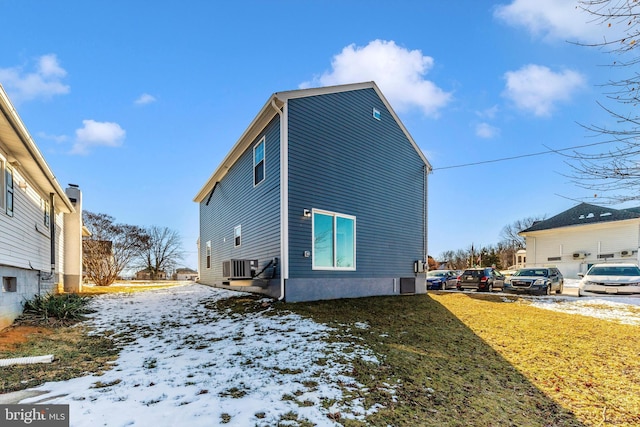 snow covered property with a yard and central air condition unit