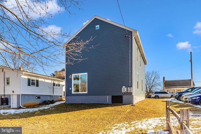 view of snowy exterior with central AC and a lawn