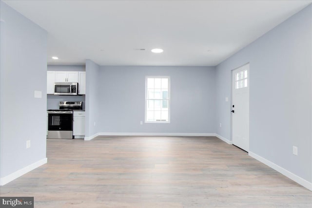 unfurnished living room featuring a wealth of natural light and light hardwood / wood-style flooring