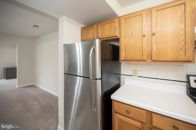 kitchen with tasteful backsplash, light colored carpet, and stainless steel refrigerator