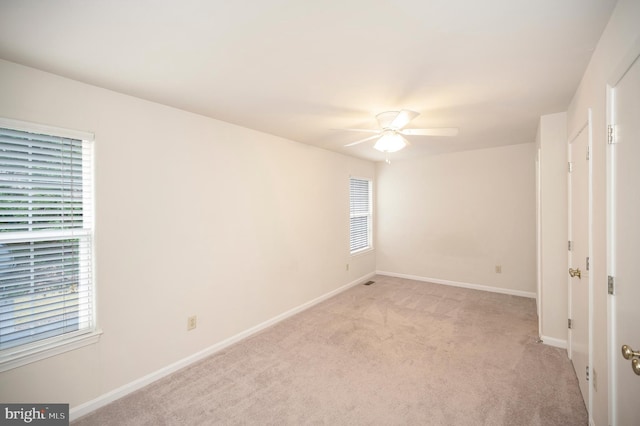 carpeted spare room with a wealth of natural light and ceiling fan