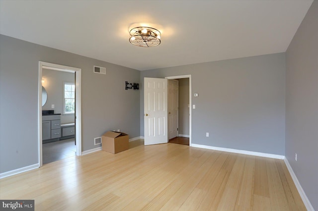 empty room featuring baseboards, visible vents, and light wood-style floors