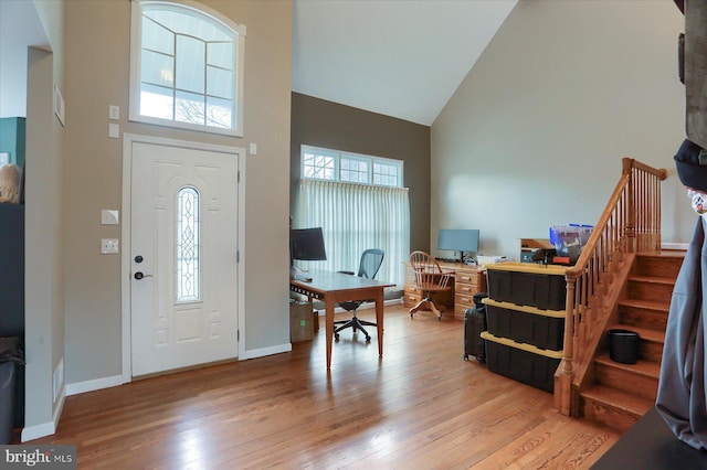 foyer with stairs, high vaulted ceiling, light wood-type flooring, and baseboards