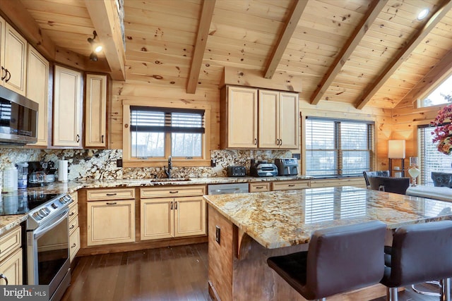 kitchen with vaulted ceiling with beams, a sink, dark wood-type flooring, appliances with stainless steel finishes, and backsplash