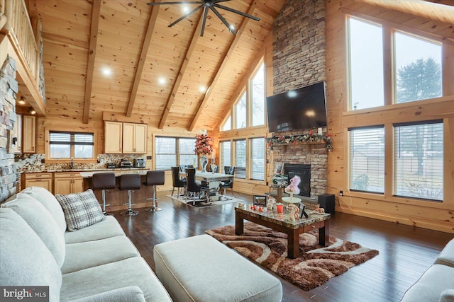 living area with high vaulted ceiling, dark wood-style flooring, a stone fireplace, wood ceiling, and beamed ceiling