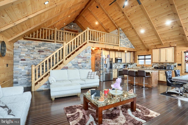 living area featuring stairway, dark wood-style floors, high vaulted ceiling, wooden ceiling, and beamed ceiling