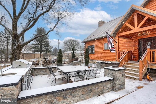 snow covered patio featuring grilling area and outdoor dining area