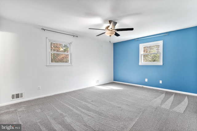 spare room with a wealth of natural light, baseboards, visible vents, and carpet flooring