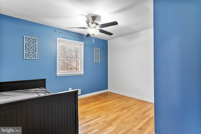 unfurnished bedroom with light wood-style flooring, baseboards, and a ceiling fan