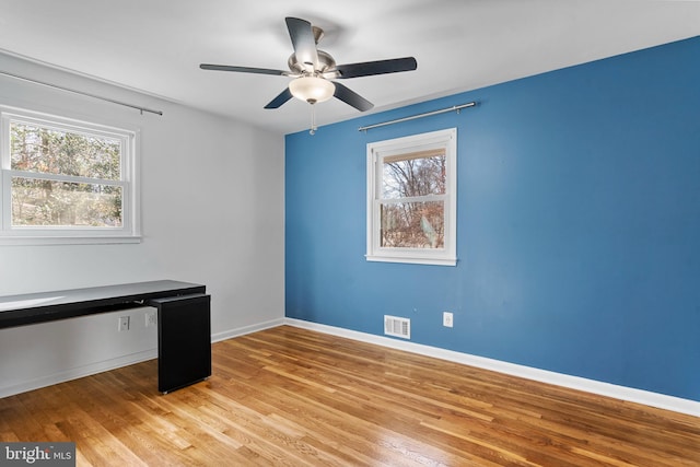 unfurnished office featuring visible vents, ceiling fan, light wood-style flooring, and baseboards