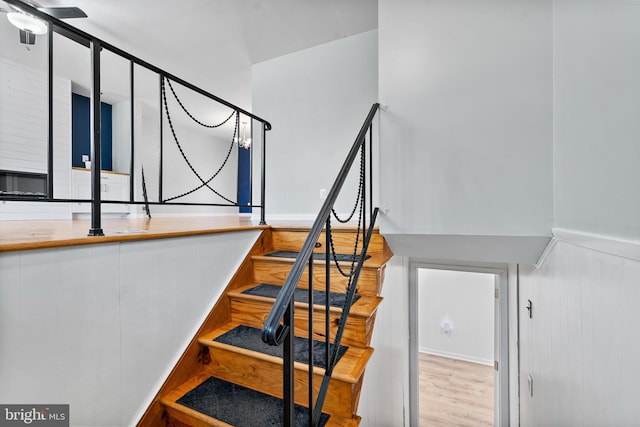 stairway with wainscoting and wood finished floors