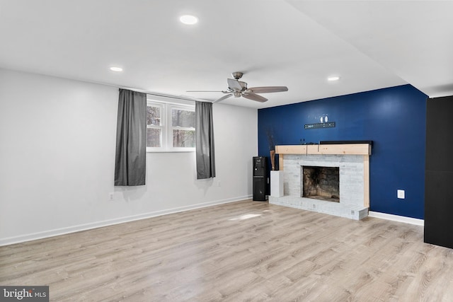 unfurnished living room with a ceiling fan, a fireplace, light wood-style flooring, and baseboards