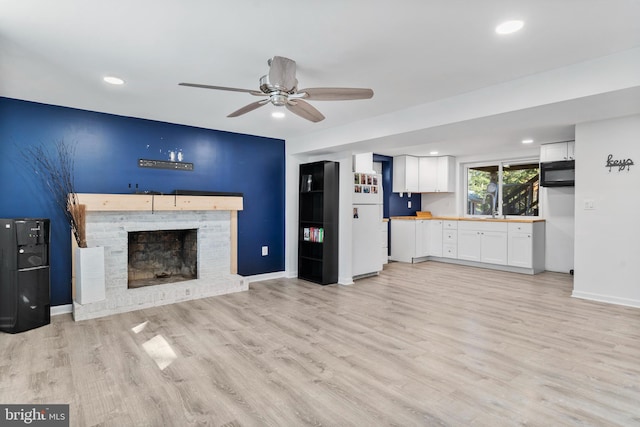 unfurnished living room featuring baseboards, a ceiling fan, light wood-style flooring, a fireplace, and recessed lighting