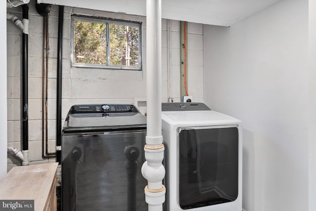 laundry area featuring concrete block wall, laundry area, and independent washer and dryer