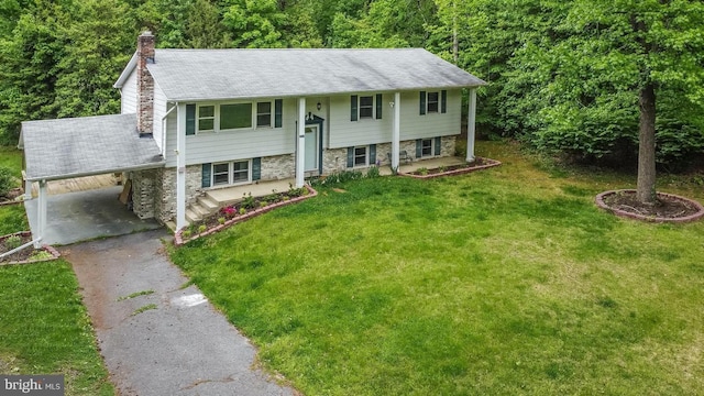 bi-level home featuring a chimney, an attached carport, stone siding, driveway, and a front lawn