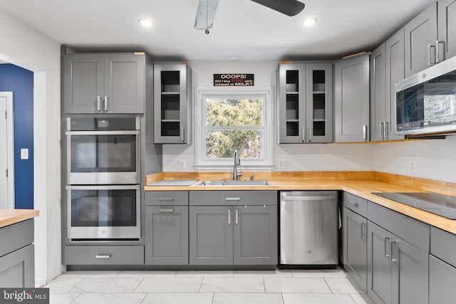 kitchen with glass insert cabinets, stainless steel appliances, a sink, and gray cabinetry