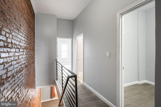 hallway featuring brick wall and dark hardwood / wood-style flooring