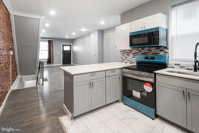 kitchen with sink, gray cabinetry, tasteful backsplash, stainless steel range with electric stovetop, and kitchen peninsula