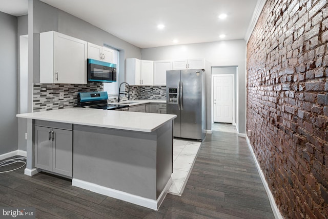 kitchen featuring white cabinetry, sink, kitchen peninsula, and appliances with stainless steel finishes