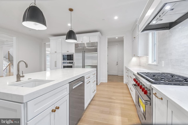 kitchen with sink, white cabinetry, built in appliances, light stone counters, and custom range hood