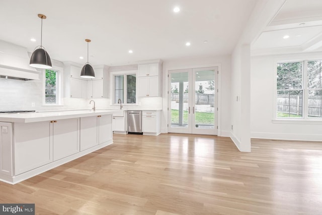 kitchen with tasteful backsplash, hanging light fixtures, light wood-type flooring, stainless steel dishwasher, and white cabinets