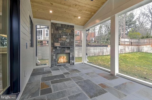 unfurnished sunroom featuring wood ceiling, lofted ceiling, and an outdoor stone fireplace