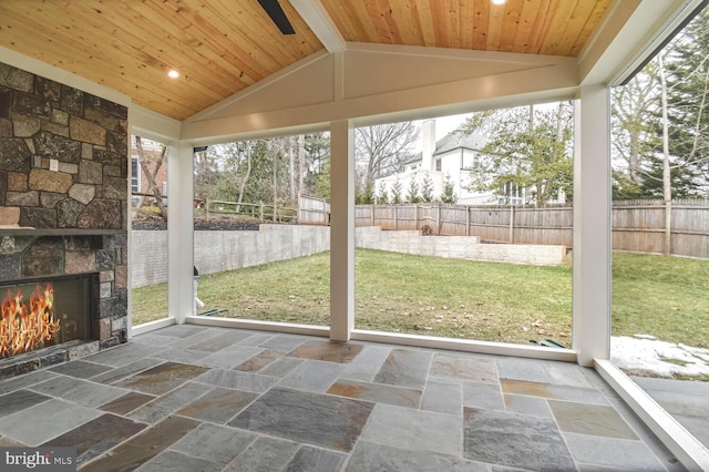 unfurnished sunroom with an outdoor stone fireplace, lofted ceiling, and wooden ceiling