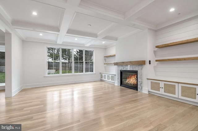 unfurnished living room featuring beamed ceiling, coffered ceiling, and light hardwood / wood-style flooring