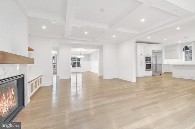 unfurnished living room with a high end fireplace, coffered ceiling, beam ceiling, and light hardwood / wood-style flooring