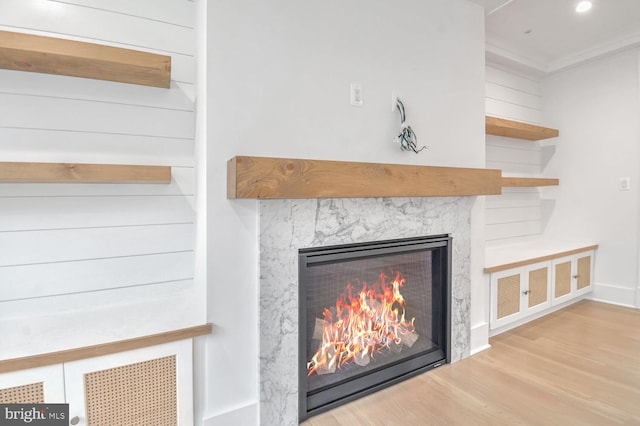 room details with hardwood / wood-style flooring, a high end fireplace, and ornamental molding