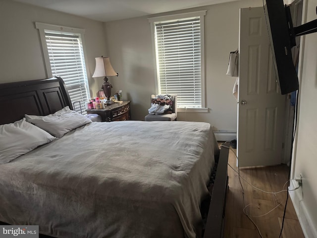 bedroom featuring a baseboard heating unit and dark hardwood / wood-style floors