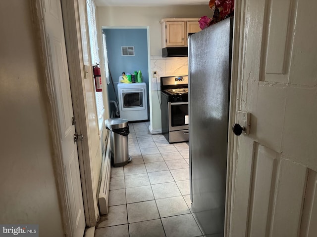 kitchen with light tile patterned floors, stainless steel appliances, decorative backsplash, washer / dryer, and exhaust hood