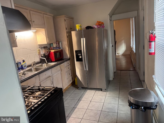 kitchen with stainless steel refrigerator with ice dispenser, black stove, sink, light tile patterned floors, and backsplash