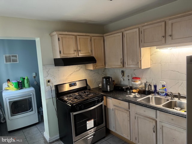 kitchen featuring sink, light tile patterned floors, stainless steel range with gas cooktop, washer / clothes dryer, and backsplash