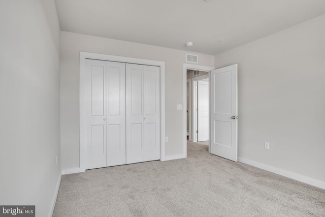 unfurnished bedroom with baseboards, visible vents, carpet floors, and a closet